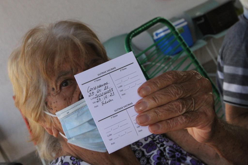 Mulher mostra cartão de vacinação contra a Covid-19 em Betim
